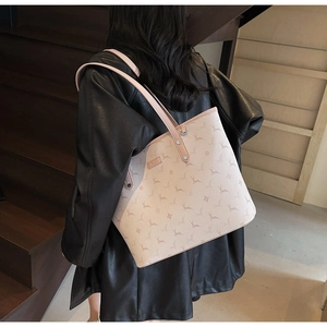 Detail of beige tote bag featuring reindeer monogram print and slim leather shoulder straps