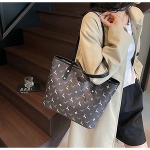 Close-up of a large tote bag with deer and star patterns worn by a model in a beige coat