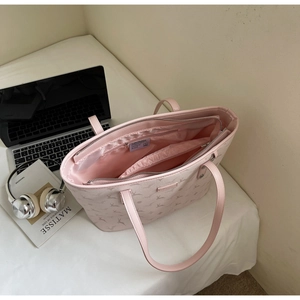 Pink tote bag interior with satin lining and compartments near books and headphones