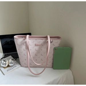 Close-up of a pink tote bag with deer print next to a laptop and headphones on a desk