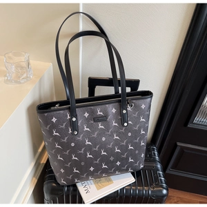 Detail of grey patterned tote bag placed on a black suitcase in a minimalist setting