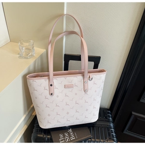 Detail of light pink tote bag with deer pattern placed on travel suitcase
