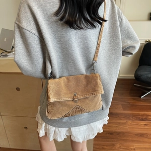 Sac bandoulière en toile lavée marron rétro porté par un mannequin dans un cadre épuré