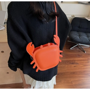 Creative orange crab crossbody bag shown on a black sweater for street style look