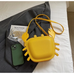 Detailed macro view of yellow crab-shaped crossbody bag with lychee texture and thin strap