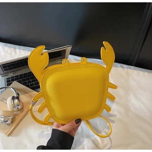 Detailed view of yellow crab-shaped shoulder bag featuring textured faux leather and 3D legs