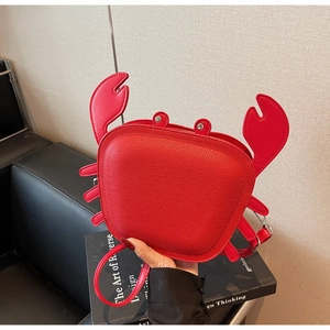 Macro view of red crab-shaped leather crossbody bag with lifelike claws and silver rivet eyes