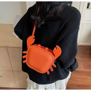Detail shot of orange crab-shaped crossbody bag worn over a black sweater