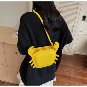 Close-up of a bright yellow crab-shaped crossbody bag made from lychee grain leather
