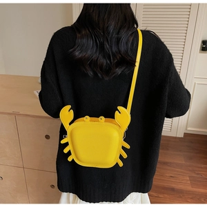 Detail of creative yellow crab-shaped crossbody bag with 3D pincers and lychee leather texture