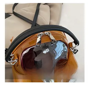 Detail showing the brown glossy leather car-shaped bag with a black cylindrical handle