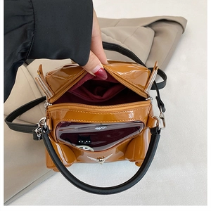 Detailed interior of caramel car-shaped handbag with glossy finish and dual zipper pockets