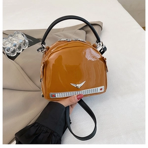Detailed macro view of car-shaped handbag in vintage brown patent leather with metal logo