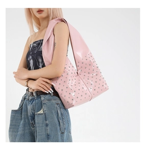 Rosafarbene Hobo-Tasche aus Lackleder mit Nieten, getragen von einem Modell auf Weiß