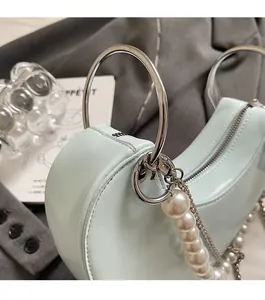 Dettaglio della borsa a cuore blu menta con manico ad anello argento e catena di perle