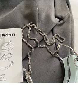 Dettaglio borsa verde menta con tracolla a catena d'argento e manico circolare in metallo