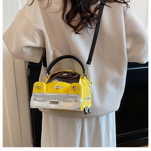 Detailed view of yellow vintage car-shaped handbag worn over the shoulder by a model