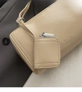 Dettaglio della borsa a tracolla beige cilindrica con cuciture e mini portamonete