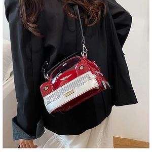 Detailed side view of a red vintage car-shaped handbag with gold rivet headlights and strap
