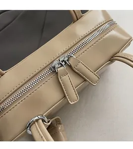 Dettaglio della doppia chiusura a zip argentata su una borsa a tracolla beige da donna