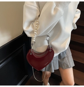 Dettaglio borsa a cuore in pelle bordeaux con manico di perle e tracolla a catena argento