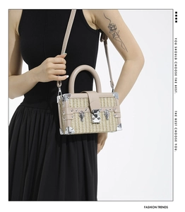 Detail of woven straw box bag featuring silver corner protectors and elegant metal lock