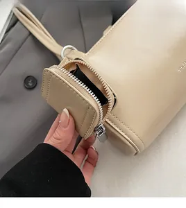 Dettaglio della borsa a spalla beige cilindrica con mini pochette coordinata e texture opaca