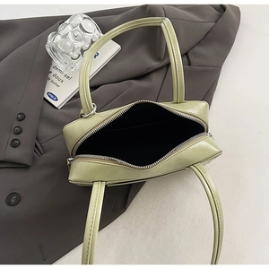 Detail view of the open zipper compartment and black lining of a green baguette bag