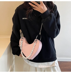 Dettaglio borsa rosa a forma di cuore con tracolla di perle e finiture in argento