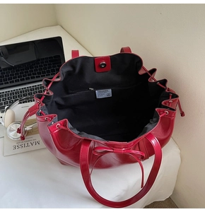 Detail view of red glossy leather tote bag with black interior lining and inner pockets
