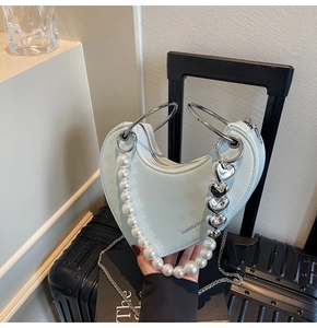 Dettaglio borsa a cuore azzurra con catena di perle e accessori in metallo argento