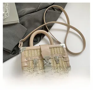 Detail of woven straw box bag with silver metal corner protectors and leather top handle