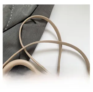 Detail of beige woven crossbody bag showing leather strap stitching and silver metal buckle