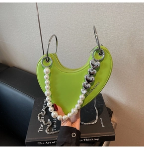Dettaglio della borsa a cuore verde neon con perla e tracolla a catena argento