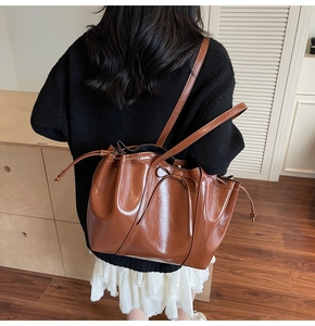 Brown faux leather tote bag with bow detail shown on shoulder for sizing and scale