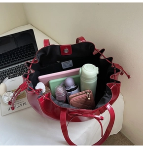 Detailed interior of red glossy tote bag showing large capacity and magnetic buckle closure