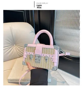 Macro detail of straw woven box bag with pink leather trim and metal corner protectors