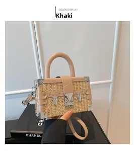 Detail of khaki straw box bag with brown leather trim and metallic corner protectors