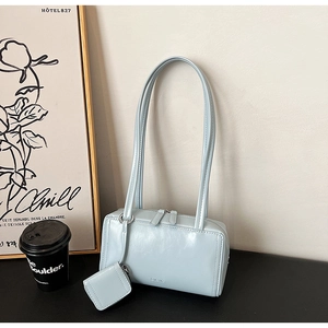 Dettaglio borsa a tracolla in pelle lucida azzurra con mini borsa e logo EMIS