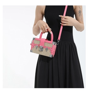Close-up of woven straw box bag with pink leather trim and vintage metal lock