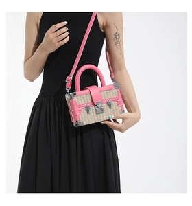 Detail of pink leather and straw mini suitcase bag worn by model on black dress