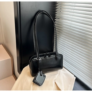 Close-up of black glossy leather underarm bag with a matching mini coin purse detail