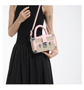 Detail of pink faux leather and woven straw crossbody box bag with metallic hardware