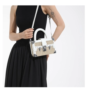 Detail of a vintage box straw bag with white leather trim and metallic corner protectors
