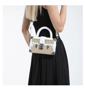 Detail view of woven straw box bag with white leather trim and metallic silver hardware