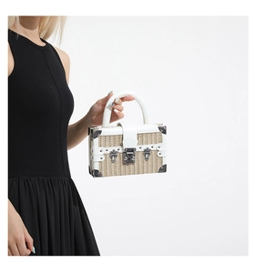 Detailed close-up of woven straw box bag with white leather trim and vintage metal lock