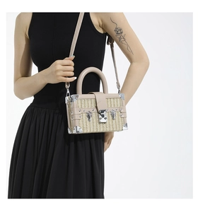 Detailed close-up of straw-woven box bag featuring silver corner protectors and hardware