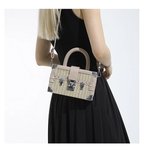 Detail view of woven straw box bag with leather trim and adjustable shoulder strap