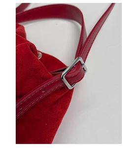 Dettaglio macro della borsa a tracolla in pelle scamosciata rossa con fibbie in metallo