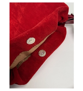 Dettaglio della borsa a secchiello in camoscio rosso con chiusura magnetica e fodera